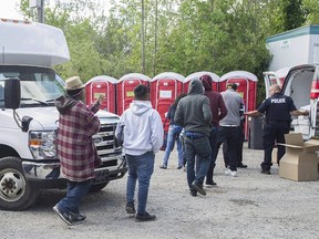 Asylum seekers line up to receive boxed lunches after entering Canada from the United States at Roxham Road in Hemmingford, Que., Wednesday, August 9, 2017. THE CANADIAN PRESS/Graham Hughes