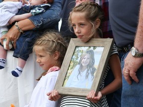 Tim Miller/The Intelligencer
Kendall (left) and Taylor Trudeau (right) hold up a picture of their older sister, Emily, while standing with the rest of their family at the Hastings County Plowing Match and Farm Show on Wednesday in Belleville. Emily's death in a 2014 farming accident has led to a push for 911 signage on all rural properties.