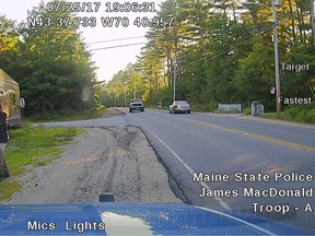 This Tuesday, July 25, 2017 patrol car dashboard camera image released by the Maine State Police shows a man strolling down a street in Hollis, Maine, who police said was wearing a clown mask with a machete taped to his amputated arm. Police said the man, Corey Berry, 31, of Hollis, was arrested and charged with criminal threatening. He was released after posting bail. (Maine State Police via AP)