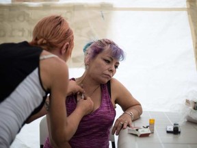 Drug user Joanne is injected with heroin by friend Angie at a pop up safe injection site in Moss Park. Toronto, Ont., August 13, 2017. NICK KOZAK / POSTMEDIA