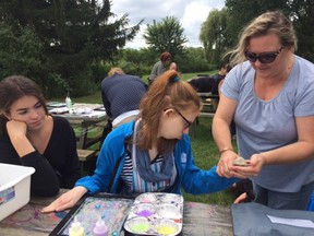 Deaf-blind artist Grace Giles is assisted with her art project by summer student Rachel Lund, left, and supervisor intervenor Connie Wiseman. (HEATHER RIVERS, Sentinel-Review)