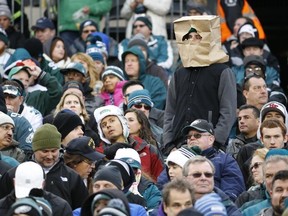 In this Nov. 22, 2015, file photo, a fan wears a paper bag on his head in the stands of Lincoln Financial Field during NFL action between the Philadelphia Eagles and the Tampa Bay Buccaneers in Philadelphia. The obituary for an Eagles fan who died Aug. 18, 2017, stated that he wanted 8 members of the team to serve as pallbearers so the Eagles could let him down "one last time." (Julio Cortez/AP Photo/Files)