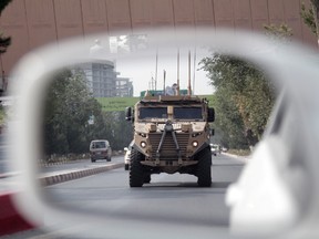 A patrolling U.S. armoured vehicle is reflected in the mirror of a car in Kabul, Afghanistan, on Aug. 23. In a national address Monday night, U.S. President Donald Trump reversed his past calls for a speedy exit and recommitted the United States to the 16-year-old conflict, saying U.S. troops must "fight to win." (Rahmat Gul/The Associated Press)