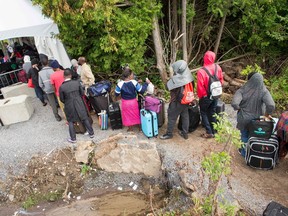 A long line of asylum seekers wait to illegally cross the Canada/US border near Champlain, New York on August 6, 2017. In recent days the number of people illegally crossing the border has grown into the hundreds.(GEOFF ROBINS/AFP/Getty Images)