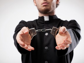 In this stock photo, a priest is seen in handcuffs. (Getty Images)