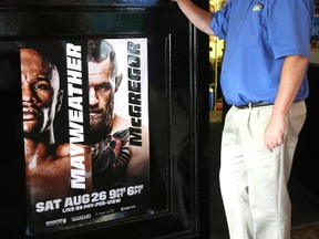 Dennis Winkler of Winks on Richmond Street shows off a poster promoting the Mayweather/McGregor pay-per-view prize fight they're showing Saturday in London. (MIKE HENSEN, The London Free Press)