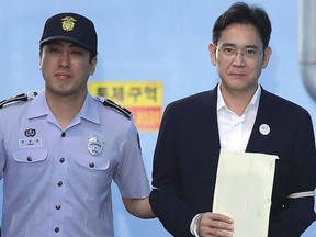 Samsung Electronics Co. vice-chairman Lee Jae-yong, right, leaves after his verdict trial at the Seoul Central District Court Friday, Aug. 25, 2017 in Seoul, South Korea. The court sentenced the billionaire Samsung heir to five years in prison for bribery and other crimes that fed public anger leading to the ouster of Park Geun-hye as South Korea's president. (Chung Sung-Jun/Pool Photo via AP)