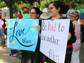 Protesters hold up their signs as a friend photographs them at a peaceful rally against racism at Victoria Park in London, Ont. on Wednesday August 16, 2017. (MIKE HENSEN, The London Free Press)