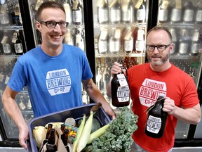Aaron Lawrence (left), a worker-owner at London Brewing Cooperative (LBC) and On the Move Organics, and Tim Stewart, a worker-owner on track, carry vegetables and beer inside the LBC brewery in east London. (Chris Montanini\Londoner)