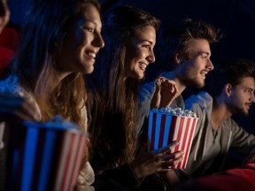 In this stock photo, moviegoers eat popcorn as they watch a film in a movie theatre. (Getty Images)