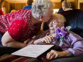 Iris Weatherwax, 97, receives a kiss from her daughter, Beverly Weatherwax, 70, of Flint, after belatedly being awarded her high school diploma in a private ceremony on Wednesday, Aug. 23, 2017, at her residence in Grand Blanc. (Terray Sylvester/The Flint Journal-MLive.com via AP)
