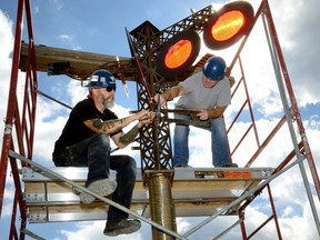 Artist Scott McKay, left, and Conor Fay install his sculpture part of the St Thomas elevated park project. (MORRIS LAMONT, The London Free Press)