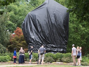 Residents and visitors look over the covered Ce statue of Confederate General Robert E. Lee in Emancipation park in Charlottesville, Va., Wednesday, Aug. 23, 2017. (AP Photo/Steve Helber)