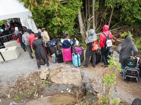 A long line of asylum seekers wait to illegally cross the Canada/U.S. border near Champlain, New York on August 6, 2017. (Getty Images)