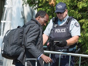 An asylum seeker, claiming to be from Eritrea, shows his passport to an RCMP officer as crosses the border into Canada from the United States Monday, August 21, 2017 near Champlain, N.Y. (THE CANADIAN PRESS/Paul Chiasson)
