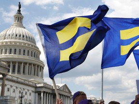 In this July 26, 2017 file photo, people with the Human Rights Campaign hold up "equality flags" during an event on Capitol Hill in Washington, in support of transgender members of the military. Officials say the Pentagon expects soon to ban transgender individuals from joining the military and to consider circumstances in which some currently serving transgender troops could remain in uniform. (AP Photo/Jacquelyn Martin)