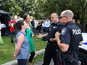 Police officers notify Lisa Wright, left, one of the  representatives of the overdose prevention site that a bylaw complaint was made against them Friday.