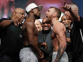 Floyd Mayweather Jr., center left, and Conor McGregor face off during a weigh-in Friday, Aug. 25, 2017, in Las Vegas. (AP Photo/John Locher)
