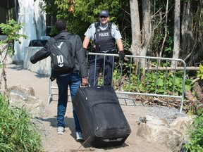 An asylum seeker, claiming to be from Eritrea, is confronted by an RCMP officer as he crosses the border into Canada from the United States on Aug. 21, 2017 near Champlain, N.Y. (Paul Chiasson/The Canadian Press)