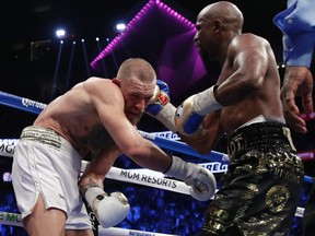 Floyd Mayweather Jr. (right) hits Conor McGregor (left) in a super welterweight boxing match in Las Vegas on Saturday, Aug. 26, 2017. (Isaac Brekken/AP Photo)