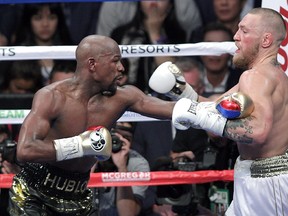 Mixed martial arts star Conor McGregor (R) competes with boxer Floyd Mayweather Jr. during their fight at the T-Mobile Arena in Las Vegas, Nevada on August 26, 2017. Floyd Mayweather outclassed Conor McGregor with a 10th-round stoppage on August 26 to win their money-spinning superfight and clinch his 50th straight victory. / AFP PHOTO / John GurzinskiJOHN GURZINSKI/AFP/Getty Images