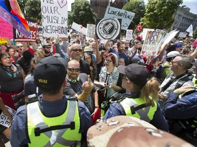 Matt Larose, supposedly on the side of peace and love, flashes a message toward Pegida protesters outside of city hall Saturday. More than 500 people condemning intolerance faced off with about 30 supporters of the Pegida. (DEREK RUTTAN, The London Free Press)