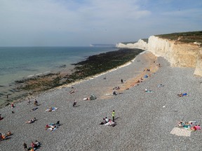 People relax on the beach at Birling Gap in Eastboune, Sussex, England, on Monday, Aug. 28, 2017. (Gareth Fuller/PA via AP)