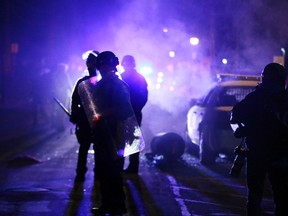 Police officers with shields watch protesters as smoke fills the streets in Ferguson, Mo., in 2014 following the fatal police shooting of 18-year-old Michael Brown. (Charlie Riedel/AP Photo/Files)