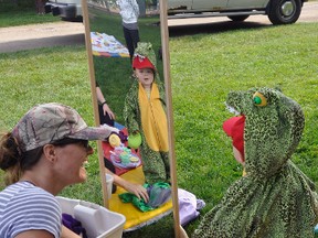 Sixteen-month-old Eric Snyder was dressed as an alligator during a visit to the Perth Care for Kids’ Books Come Alive program held at Keterson Park last Wednesday morning, Aug. 23 and he wasn’t quite sure what to make of his reflection in the mirror while mom Brittany has a laugh. Eric and big brother Owen are regulars in the Art in the Park program, too, which was also held during the cool morning which may have caused other regular visitors, if not on vacation, to stay home. ANDY BADER/MITCHELL ADVOCATE