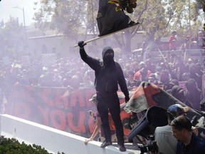 An anti-fascist demonstrator jumps over a barricade during a free speech rally Sunday, Aug. 27, 2017, in Berkeley, Calif. (AP Photo/Marcio Jose Sanchez)