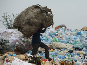 A man carrying used plastic containers which he will sell walks across the Ngong town dumping site, some 30 kilometres southwest of Nairobi on August 24, 2017. SIMON MAINA/Getty Images