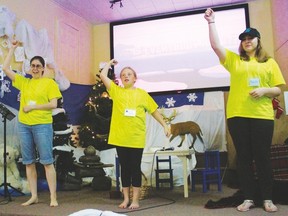 Bible School leader Verna Powley (l.) and her two assistants lead participants in an action song during Vacation Bible School.