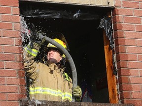 Kingston Fire and Rescue crews put out hot spots in a second floor window after an early morning fire at the townhouse development at 375 Patrick Street on Monday Aug. 28 2017. The fire to the two hits caused about $150,000 in damage. The fire jus still under investigation. (Ian MacAlpine /The Whig-Standard)