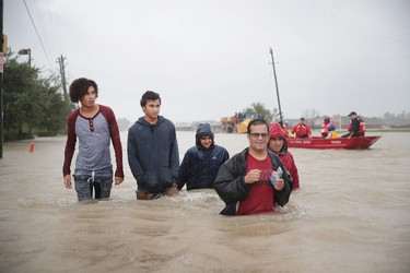 HOUSTON, TX - AUGUST 28:  People make their way out of a flooded neighborhood after it was inundated with rain water, remnants of Hurricane Harvey, on August 28, 2017 in Houston, Texas. Harvey, which made landfall north of Corpus Christi late Friday evening, is expected to dump upwards to 40 inches of rain in areas of Texas over the next couple of days.  (Photo by Scott Olson/Getty Images)