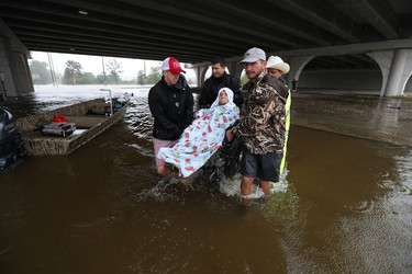 Volunteers and Harris County Sheriff deputies lift an elderly person on a wheelchair over the flooded C.E. King Parkway under the East Sam Houston North on Monday, Aug. 28, 2017, in Houston. (Steve Gonzales/Houston Chronicle via AP) ORG XMIT: TXHOU113