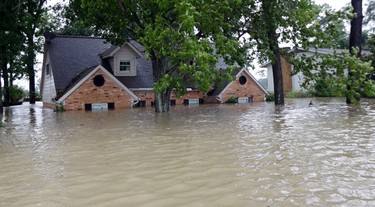 A home is surrounded by floodwaters from Tropical Storm Harvey on Monday, Aug. 28, 2017, in Spring, Texas. Homeowners suffering from Harvey flood damage are more likely to be on the hook for losses than victims of prior storms, a potentially crushing blow to personal finances and neighborhoods along the Gulf Coast. Experts say far too few homeowners have flood insurance, just two of ten living in Harvey�s path of destruction. (AP Photo/David J. Phillip) ORG XMIT: NYBZ213