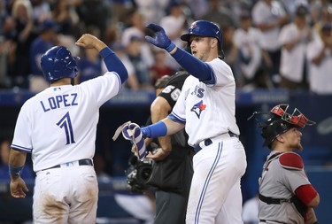 Justin Smoak #14 of the Toronto Blue Jays is congratulated by Raffy Lopez #1 after hitting a two-run home run in the ninth inning during MLB game action against the Boston Red Sox at Rogers Centre on August 28, 2017 in Toronto, Canada. (Photo by Tom Szczerbowski/Getty Images)