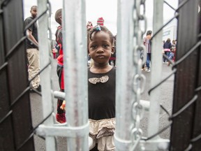 This file photo taken on August 5, 2017 shows a girl who crossed the Canada/US border illegally with her family, claiming refugee status in Canada,as she looks through a fence at a temporary detention centre in Blackpool, Quebec. The Canadian military began setting up tents near the US border on August 9, 2017 to house a surge of Haitian refugees from the United States. The modular tents being erected in the town of Saint-Bernard-de-Lacolle, 60 kilometers (38 miles) south of Montreal, are equipped with lighting and heating equipment and will accommodate up to 500 asylum seekers, the army said in a statement. (GEOFF ROBINS/AFP/Getty Images)