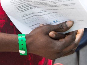 An asylum seeker holds on to his paperwork as he leaves Olympic Stadium in Montreal on Aug. 3, 2017 in Montreal. (Ryan Remiorz/The Canadian Press)