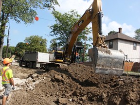 Kyle Schonauer, left, watches overhead wires while Craig Joris moves dirt on Emma Street in Sarnia Wednesday. The workers with Van Bree Drainage and Bulldozing were completing part of a $4.9 million sewer separation project. (Tyler Kula/Sarnia Observer)