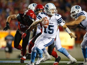 Toronto Argonauts' quarterback Ricky Ray, rights, runs from Calgary Stampeders' players during CFL action in Calgary on Aug. 26, 2017. (THE CANADIAN PRESS/Jeff McIntosh)