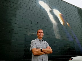 Bob Schilf stands in front the hand mural that was painted by an American artist on the exterior of the building at the Track N' Trail store on Whyte Avenue in Old Strathcona. An unknown tagger spray-painted graffiti over the mural, that has since been sprayed over with black paint. Schilf is the owner of the business and the building. (PHOTO BY LARRY WONG/POSTMEDIA)