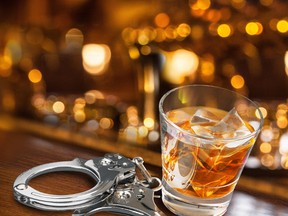 An alcoholic drink filled with ice cubes sits on a bar next to a pair of handcuffs in this stock photo. (Getty Images)