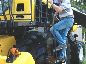 Alfred Wolf of Burgessville carries his son Duncan, 2, down from a combine at the 2016 edition of Canada's Outdoor Farm Show near Woodstock. This year's show starts Sept. 12.