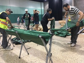 Volunteers set up cots in an emergency shelter in the Winnipeg Convention Centre for some of the 3,700 people fleeing forest fires in northern Manitoba. on Thursday, Aug.31, 2017. THE CANADIAN PRESS/Steve Lambert