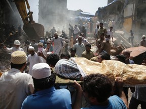 The body of a victim is carried out from the site of a building collapse in Mumbai, India, Thursday, Aug. 31, 2017. A five-story building collapsed Thursday in Mumbai, Indian’s financial capital, after torrential rains lashed western India. (AP Photo/Rafiq Maqbool)