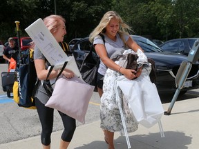 Amie Seguin, left, helps sister Rachel, 17, of Niagara Falls, move into Western University?s Saugeen-Maitland Hall as their dad, Mike, follows as the annual Labour Day weekend influx of students to London?s post-secondary schools begins. MIKE HENSEN/THE LONDON FREE PRESS