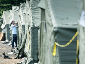 An asylum seeker readjusts his tent in a temporary camp, Tuesday, August 15, 2017 near Saint-Bernard-de-Lacolle, Que. THE CANADIAN PRESS/Paul Chiasson