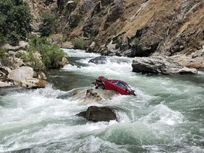 This Aug. 5, 2017, file photo provided by the Fresno County Sheriff's office shows a car in the middle of Kings River near Fresno, Calif. Authorities on Friday, Sept. 1, 2017, recovered the bodies of two Thai exchange students believed to be inside the car that plunged off a cliff more than a month ago in Central California and became lodged in a dangerous river. (Fresno County Sheriff's Office via AP/Files)