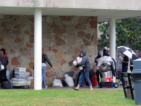 Families take shelter during a rainy Queen's University move-in day in Kingston last year. (Steph Crosier/Whig-Standard file photo)